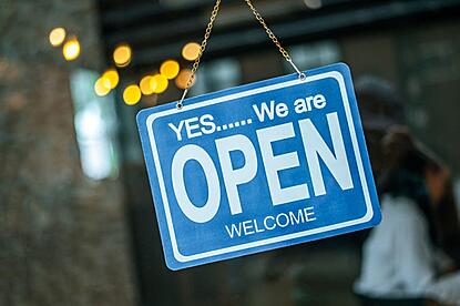 photo of an "Yes...we are open"sign hanging on a door